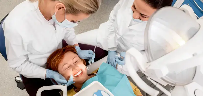Eine junge Frau ist beim Zahnarzt, Ärztin und Arzthelferin machen einen Zahncheck