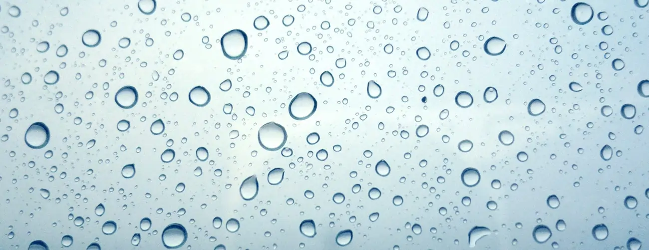 Eine Glasscheibe mit vielen Wassertröpfchen - symbolisch für Kondenswasser