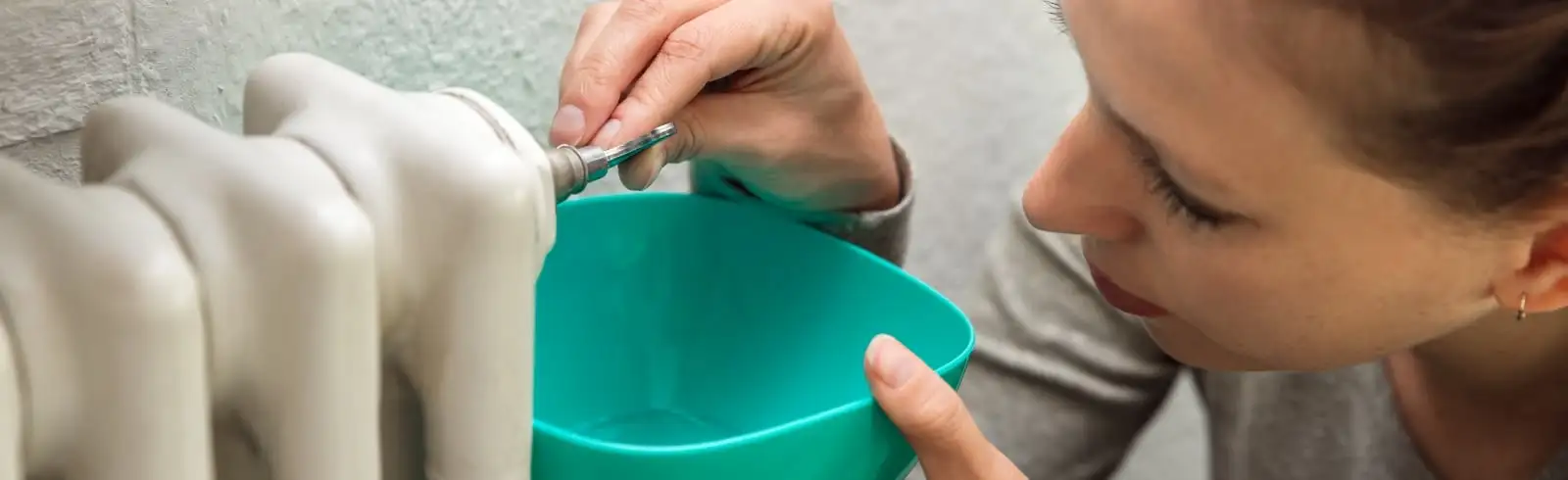 Wegen Schimmel hinter der Heizung entlüftet eine Frau die Heizung, damit sie danach besser heizt