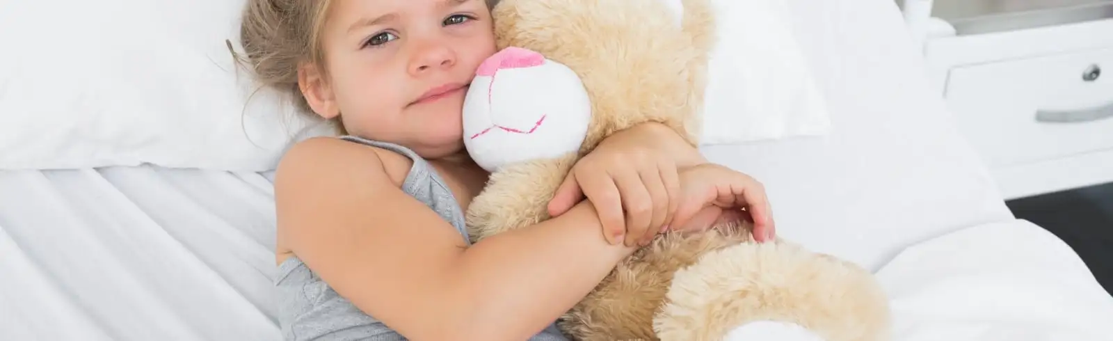 Ein trauriges und krankes Kind klammert sich an sein Kuscheltier